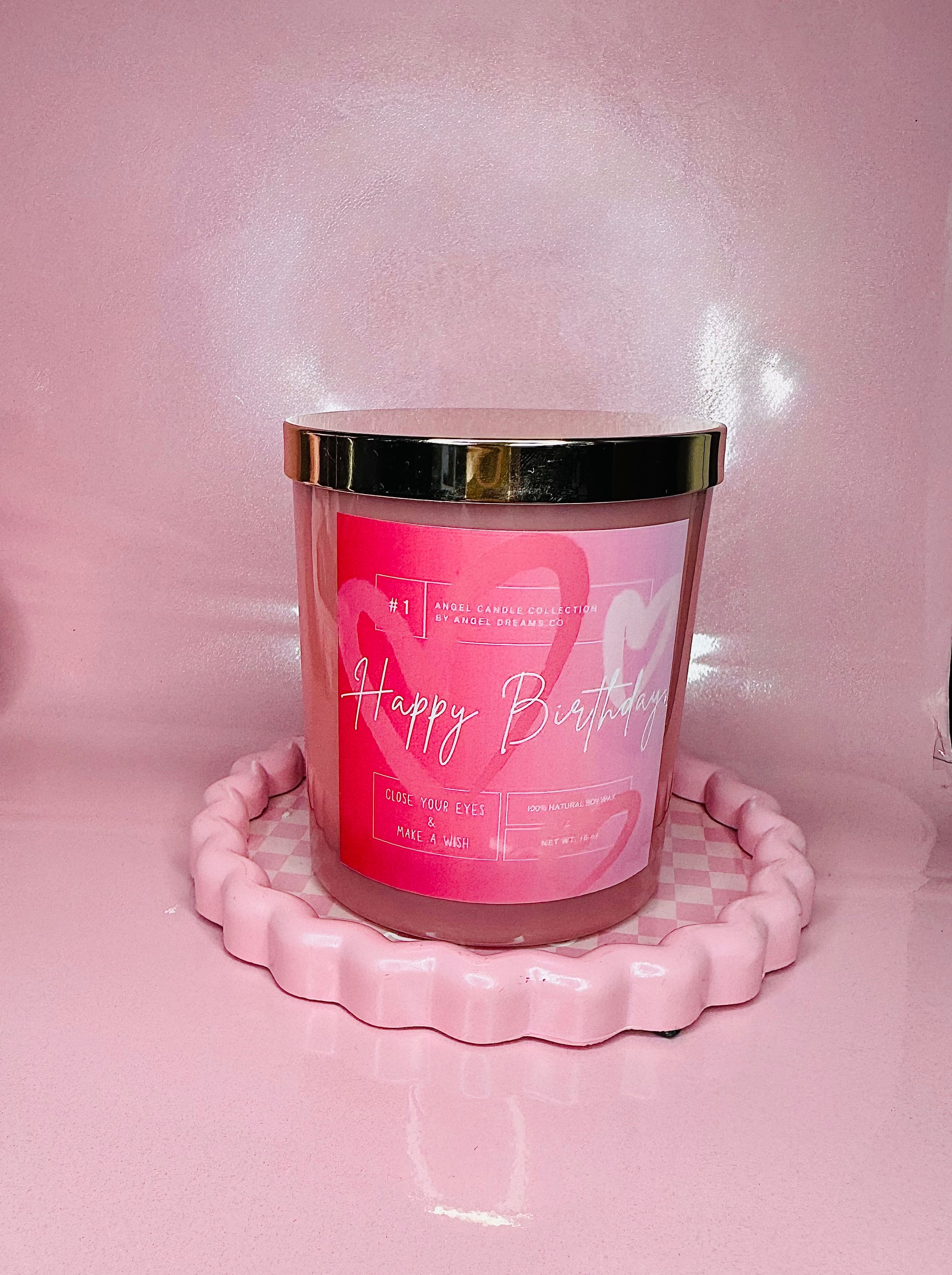Pink candle with 'Happy Birthday' text on a pink stand against a pink background
